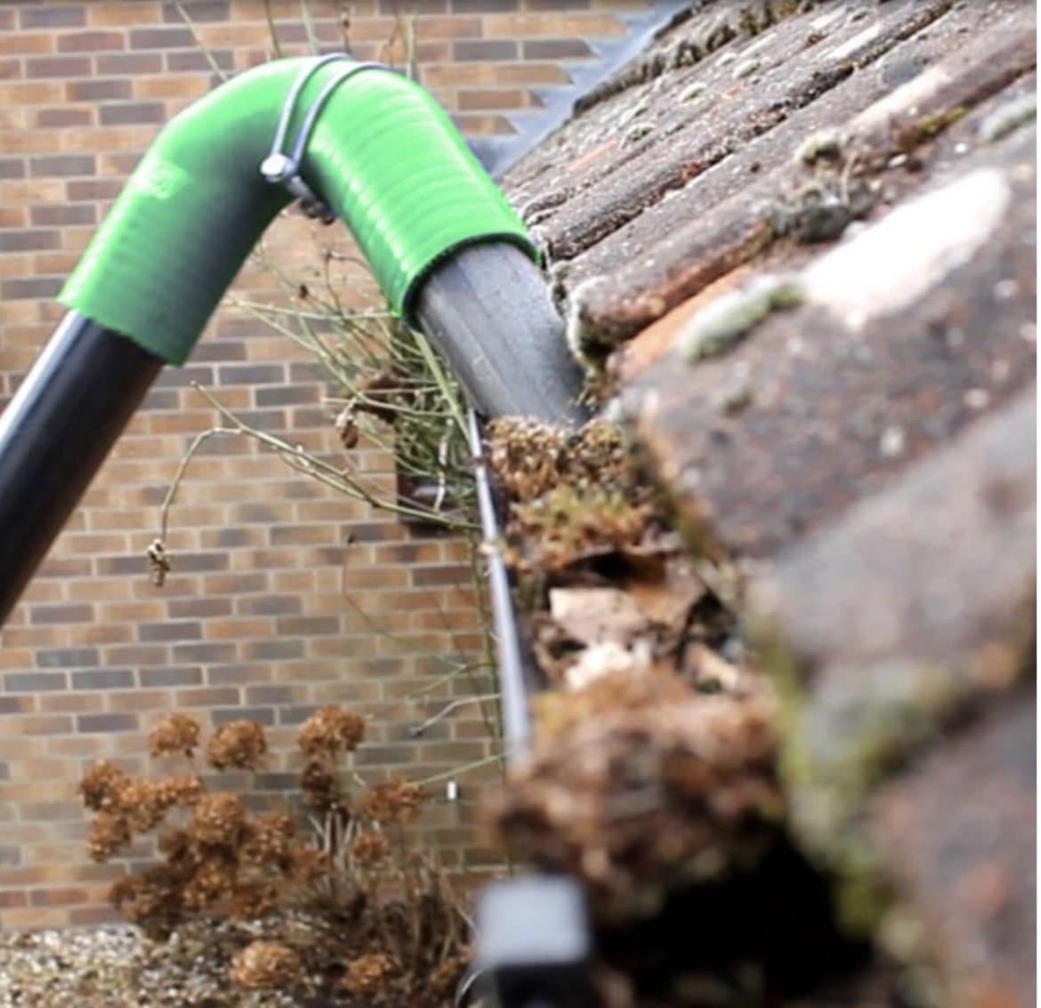 Gutter vacuum clearing moss and leaves from a blocked gutter