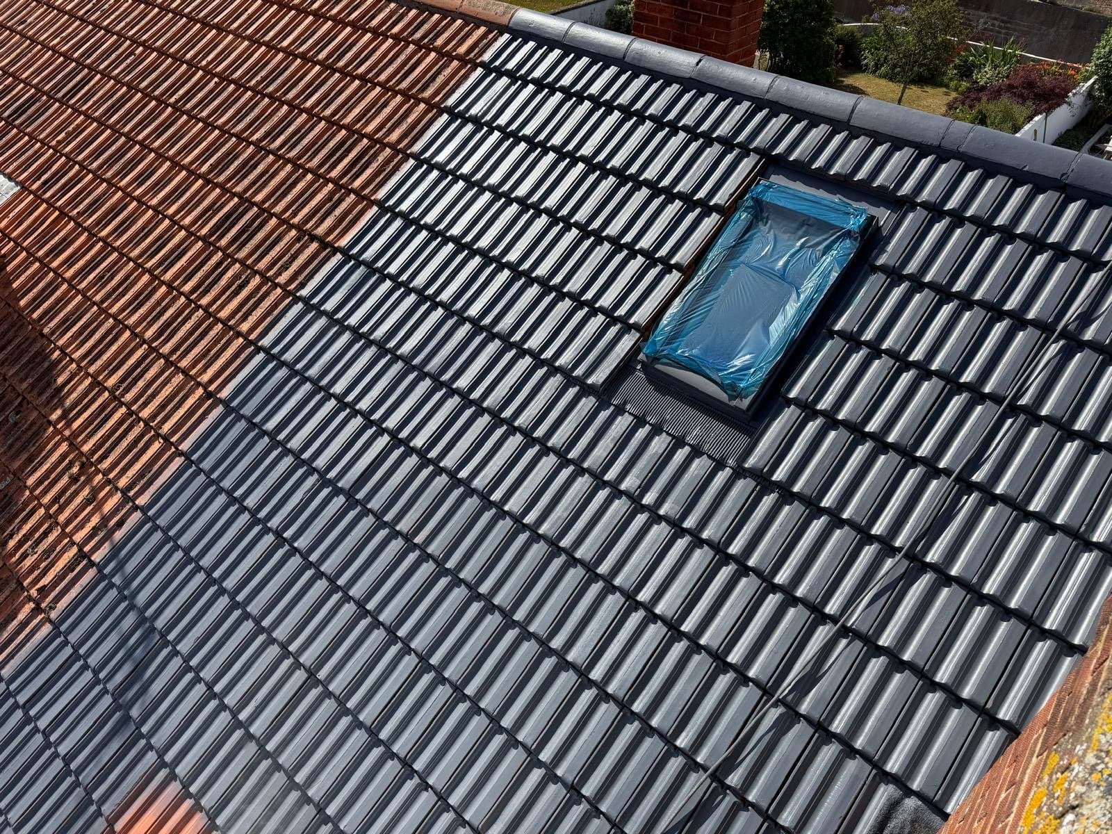 Concrete roof tiles part way through a grey protective coating
